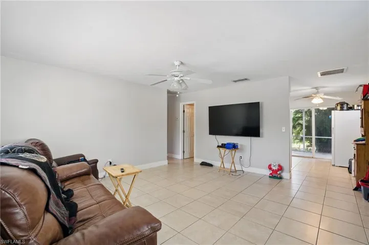 Living area with a ceiling fan, light tile patterned floors, and baseboards