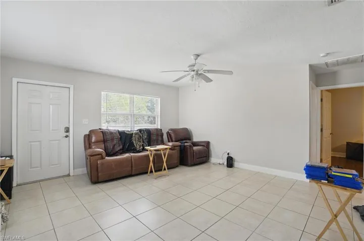 Living room featuring ceiling fan, light tile patterned floors, and baseboards