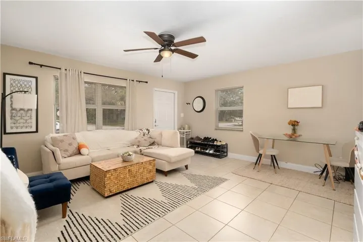Living room with ceiling fan, light tile patterned flooring, and baseboards
