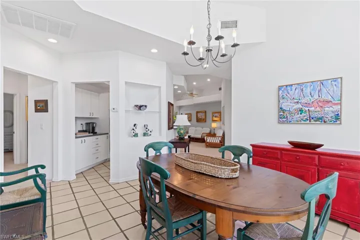 Dining area featuring vaulted ceilings, a chandelier, and tiled flooring
