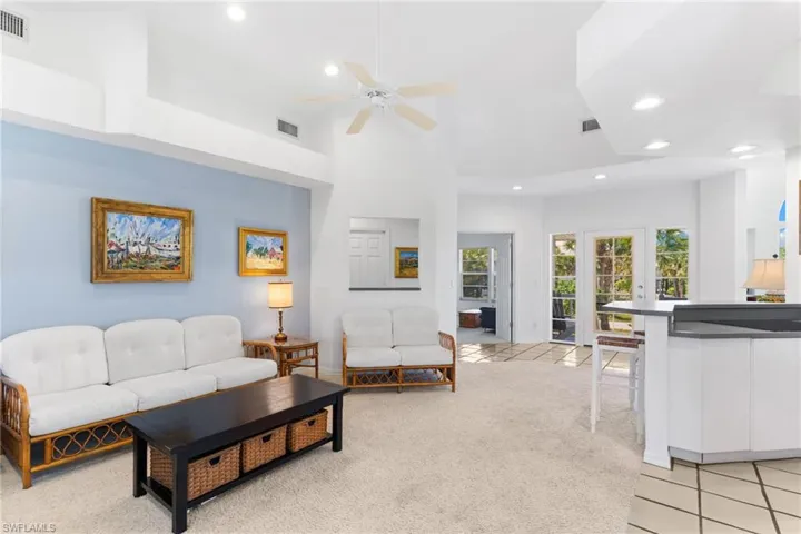 Living area featuring a light-colored carpet, a ceiling fan, and French doors leading to exterior views