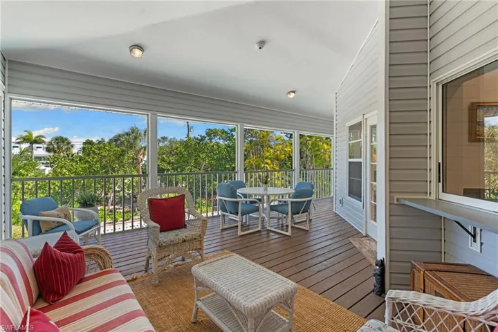 Expansive screened-in porch with a wood deck and views of lush greenery