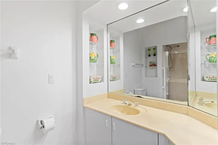 The bathroom features a vanity with a built-in sink and a large mirror, along with recessed lighting