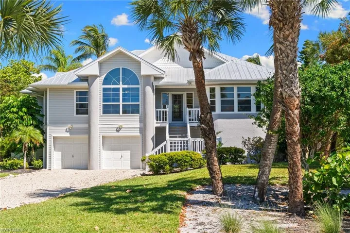The property features a two-car garage, a grand arched window, and a white metal roof