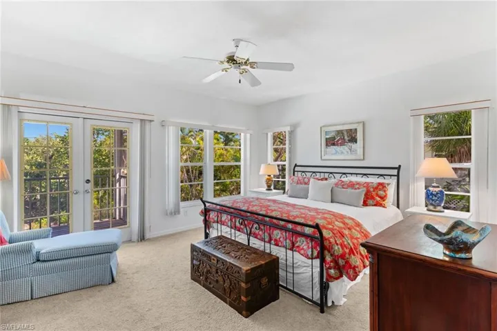 This bright room features light-colored carpeting, a ceiling fan, and white walls