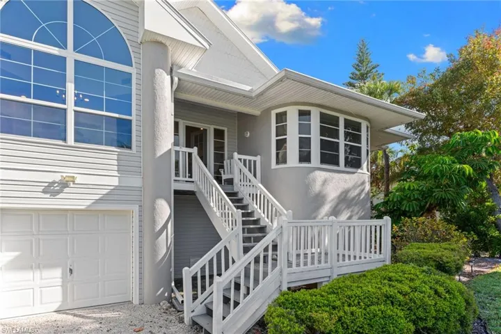 The property features a two-story design with a garage door, an exterior staircase leading to the main entrance, and an arched window