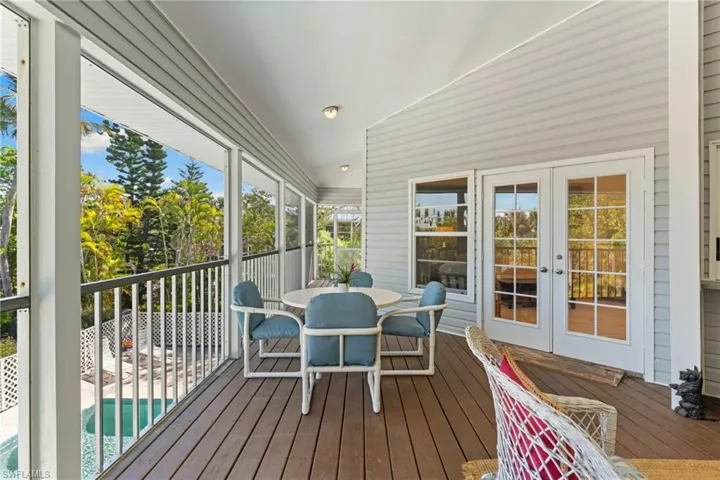 The property features a spacious screened-in porch with wood plank flooring, offering elevated views of the pool and lush trees