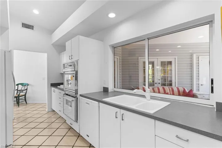 The property features a kitchen with white cabinetry, a double basin sink, and built-in stainless steel appliances