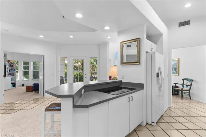Kitchen featuring white cabinetry, a dark countertop, an integrated stovetop, and a white refrigerator