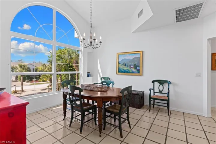 Living area featuring a large arched window with grid pattern, high ceilings, and tiled flooring
