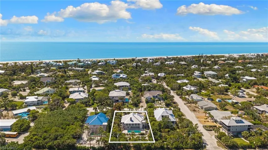 The property features a multi-story residence with a light-colored exterior and a dark roof, surrounded by mature trees
