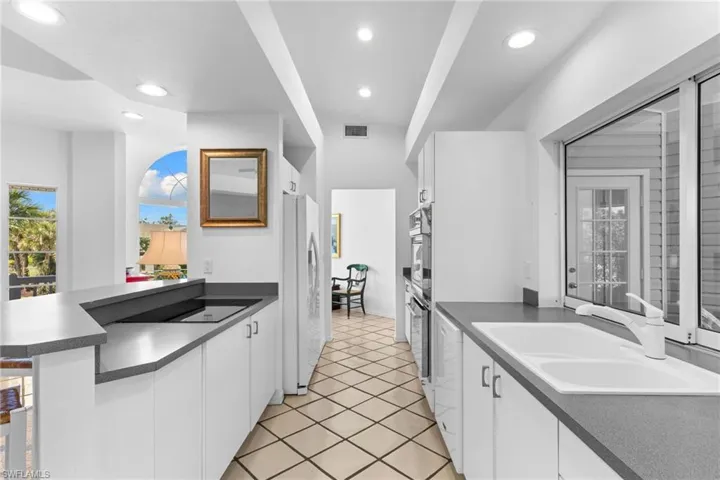 The kitchen features white cabinetry, dark countertops, and a white double-basin sink with a white faucet