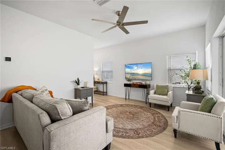 Living area with ceiling fan, light wood-type flooring, visible vents, and baseboards