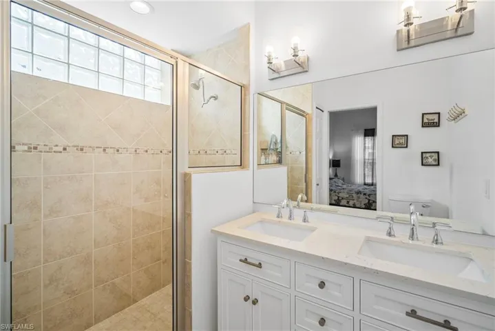 Bathroom with double vanity, a stall shower, ensuite bath, and a sink
