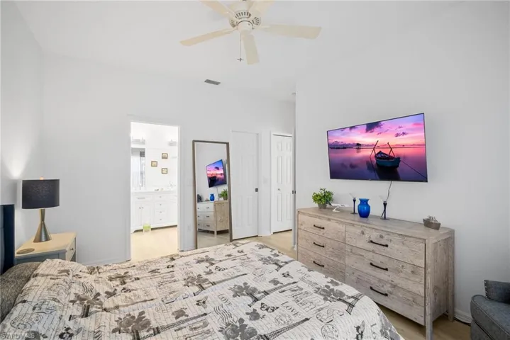 Bedroom featuring visible vents, connected bathroom, light wood-style flooring, and a ceiling fan