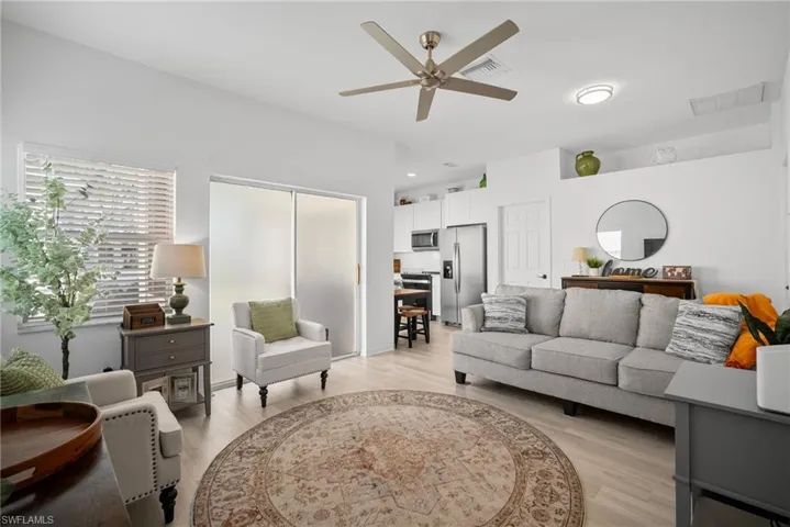 Living area with a ceiling fan, visible vents, and light wood-style flooring