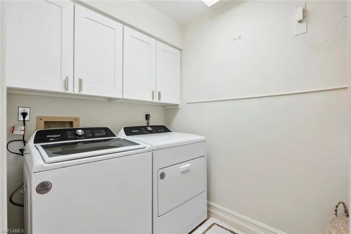 Clothes washing area featuring washer and clothes dryer and cabinets