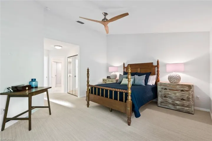 Carpeted bedroom featuring ensuite bath and ceiling fan