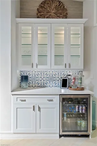 Bar featuring white cabinets, tasteful backsplash, and beverage cooler