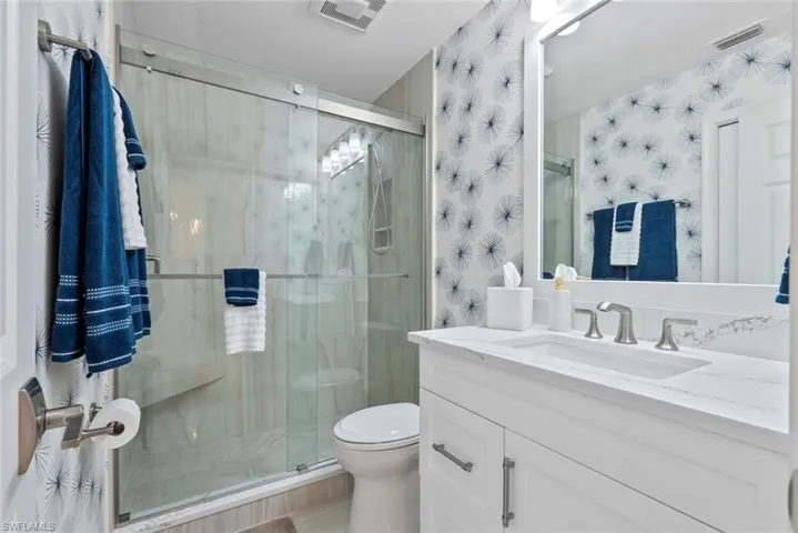 Bathroom with vanity, a shower with shower door, and toilet