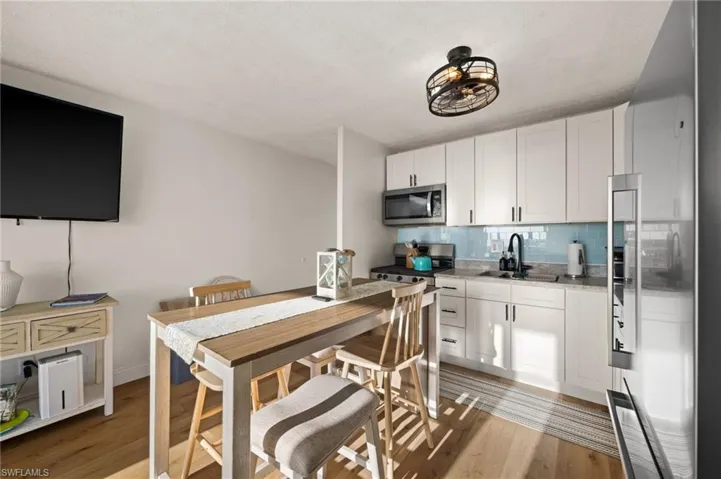 Kitchen featuring stainless steel appliances, white cabinetry, backsplash, light wood finished floors, and a textured ceiling