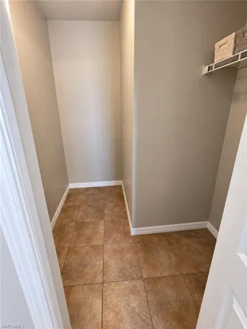Tile flooring, neutral wall color, white trim, and a built-in wire shelf