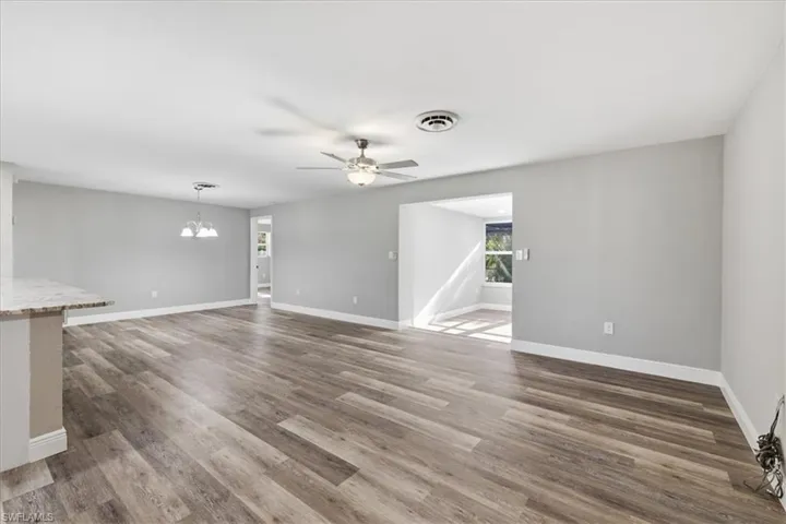 Empty Livingroom with a ceiling fan, dark wood finished floors, and a chandelier