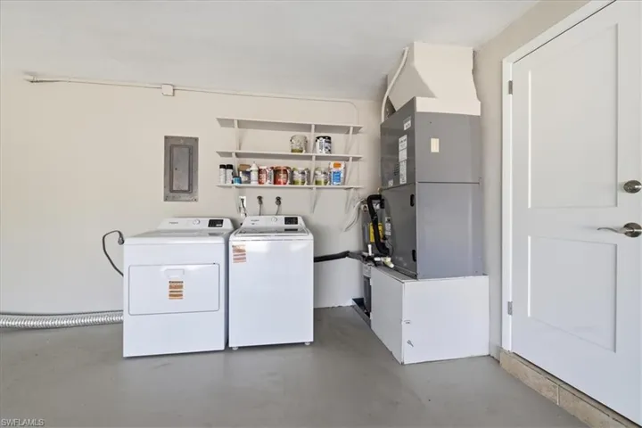 Laundry area with independent washer and dryer, concrete floors, heating unit, and electric panel