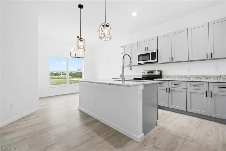 Kitchen with appliances with stainless steel finishes, a center island with sink, sink, and light hardwood / wood-style flooring