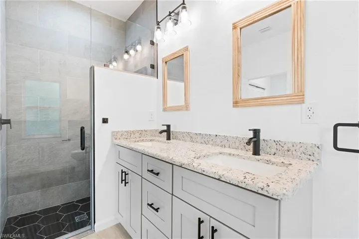 Bathroom featuring a shower with shower door and vanity