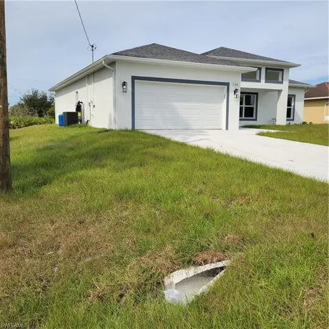View of front of home with a garage, a front lawn, and central AC unit