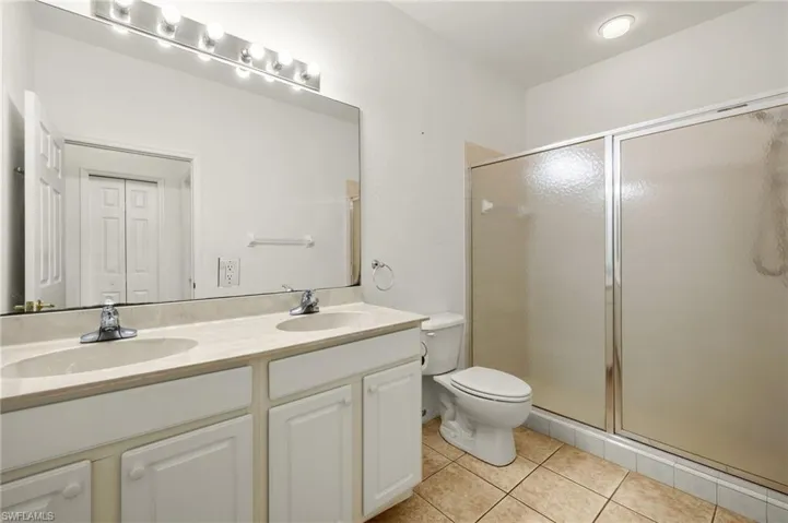 Bathroom featuring vanity, a shower with shower door, tile patterned floors, and toilet
