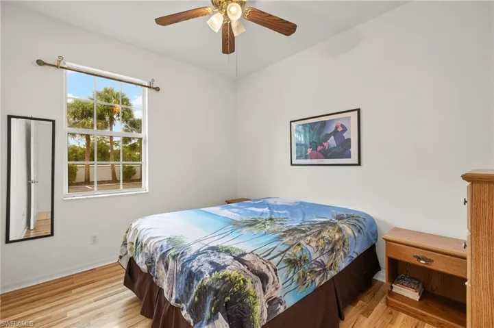Bedroom with ceiling fan, light hardwood / wood-style floors, and multiple windows