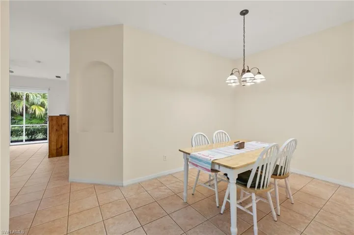 Dining area with light tile patterned flooring and a notable chandelier