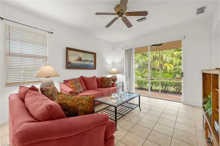 Living room with ceiling fan and light tile patterned flooring