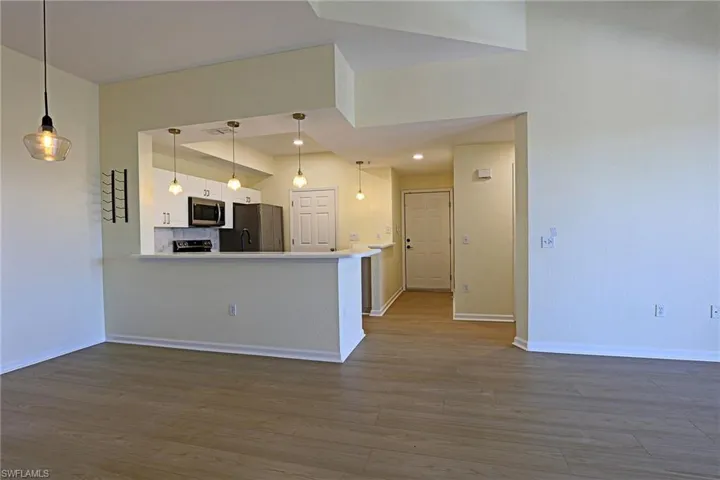 Kitchen featuring light countertops, decorative light fixtures, a peninsula, white cabinetry, and black appliances