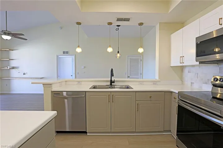 Kitchen featuring stainless steel appliances, light wood finished floors, light countertops, and decorative light fixtures