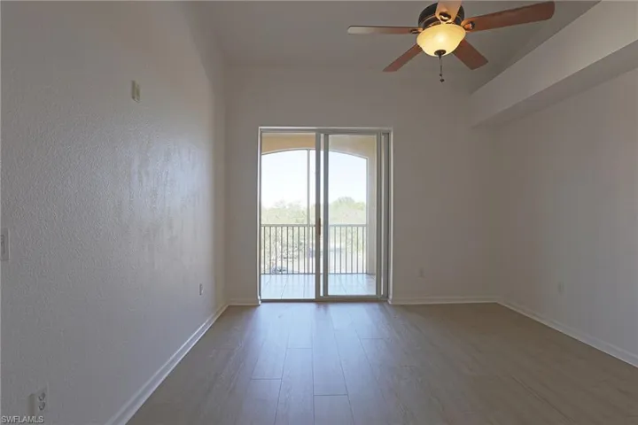 Spare room with ceiling fan, light wood finished floors, and a textured wall