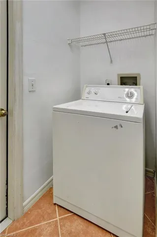 Washer machine locate indoors with upper shelf for storage.