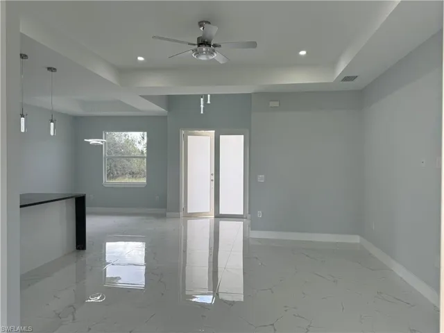 Unfurnished room featuring ceiling fan and a raised ceiling