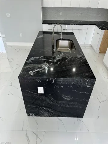 Room details featuring sink, dark stone counters, and white cabinets