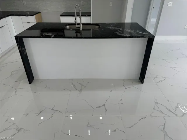 Kitchen featuring sink, white cabinets, and dark stone counters