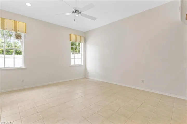 Empty room with light tile patterned flooring, a healthy amount of sunlight, and ceiling fan