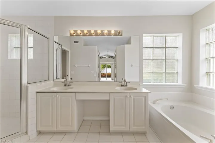 Bathroom with double vanity, separate shower and tub, tile patterned floors, and plenty of natural light