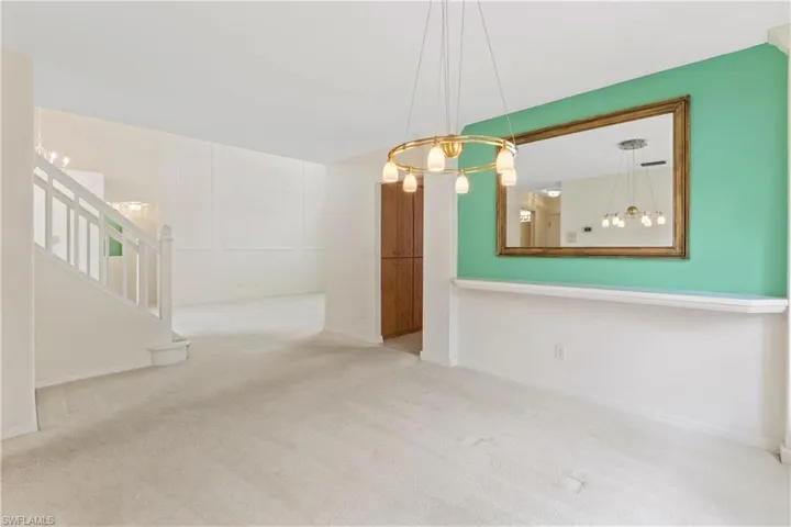 Unfurnished living room with an inviting chandelier and light colored carpet