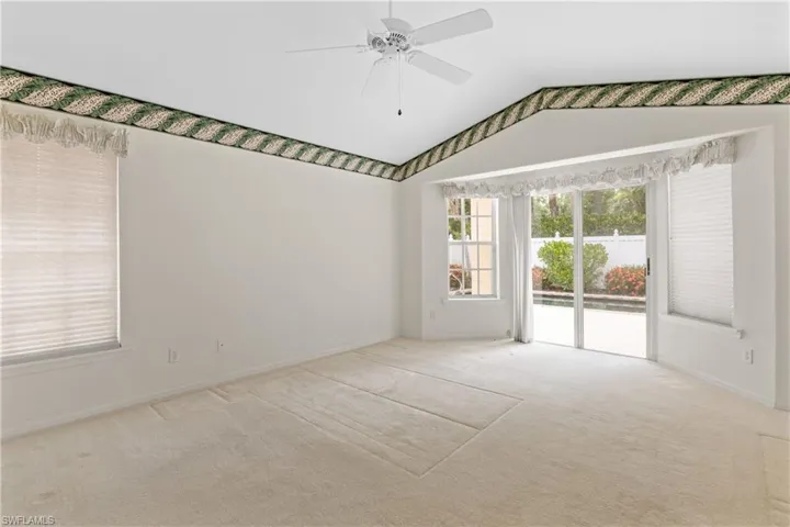 Carpeted spare room featuring ceiling fan and vaulted ceiling