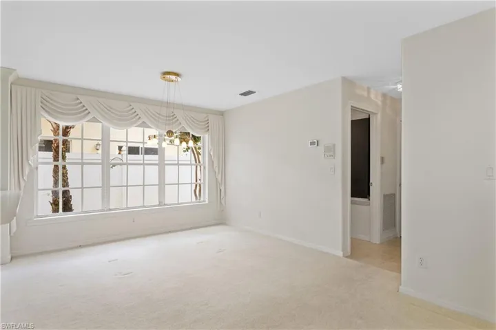 Carpeted empty room featuring a chandelier