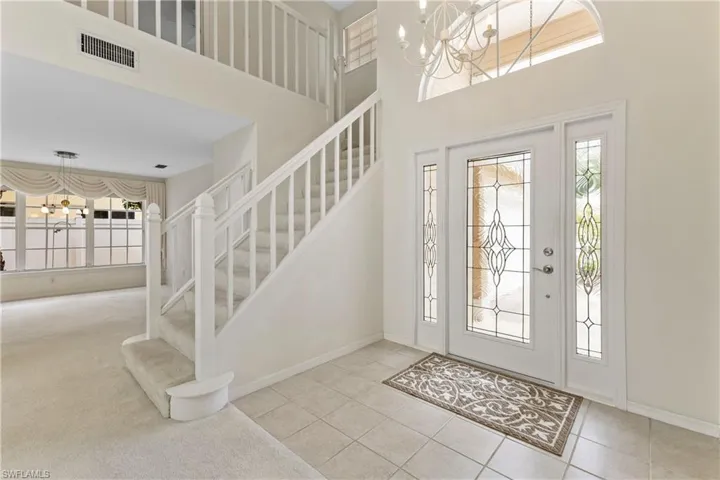 Carpeted entryway with a chandelier