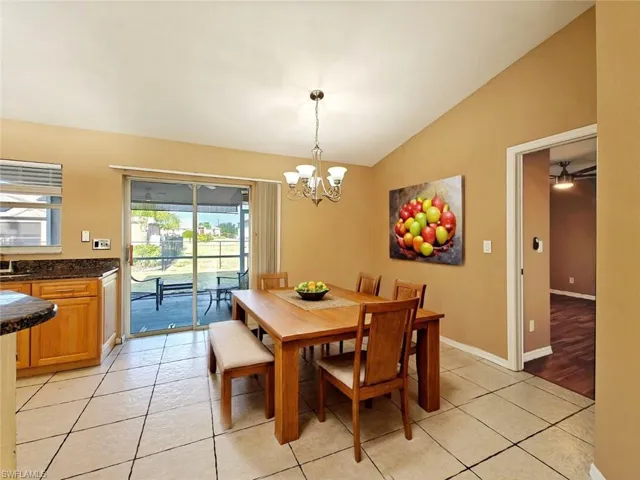 Dining room with baseboards, a chandelier, light tile patterned floors, and lofted ceiling