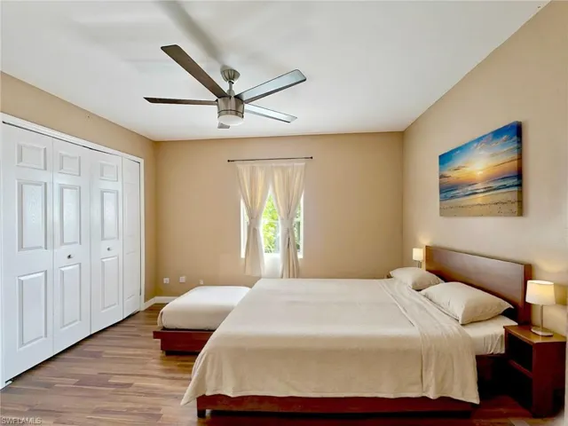 Bedroom with a closet, a ceiling fan, baseboards, and wood finished floors